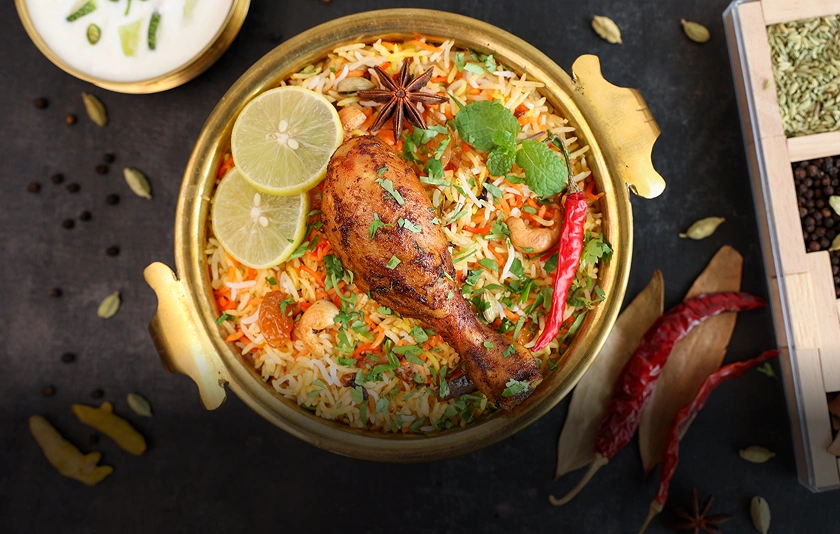 Spicy biryani with chicken drumstick and garnish.
